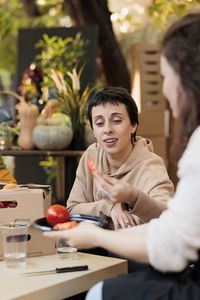 Portrait of young woman using mobile phone while sitting on table