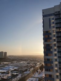 Buildings in city against clear sky during sunset