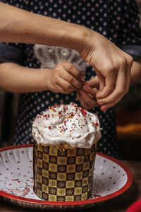 Midsection of person holding ice cream on table