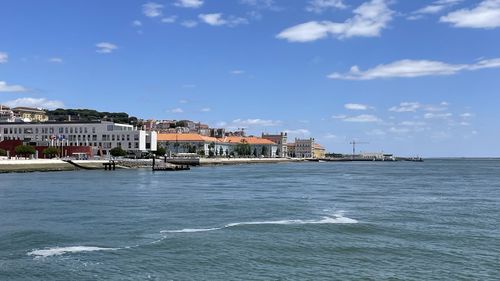Buildings at waterfront against cloudy sky