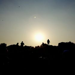 Silhouette people standing on landscape against clear sky during sunset