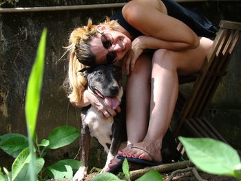 Portrait of smiling woman with dog sitting on chair