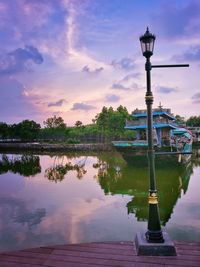 Street light by lake against sky during sunset