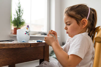 Side view of girl doing craft at home