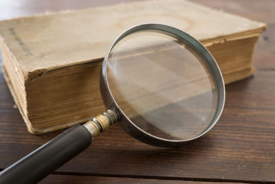 High angle view of magnifying glass with old book on table