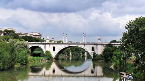 Arch bridge over river against sky