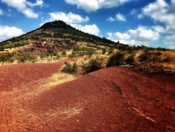 Scenic view of road by mountains against sky