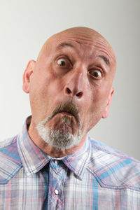 Close-up portrait of senior man against white background