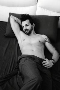 Portrait of shirtless man lying on bed