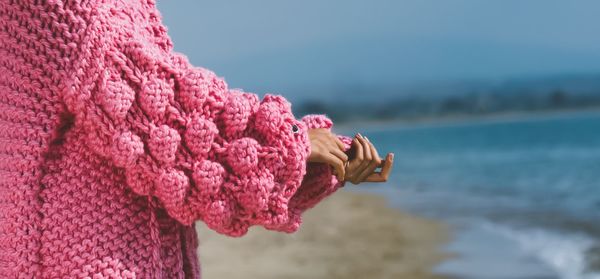 Close-up of hand on pink sea against sky