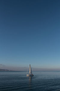 Sailboat sailing on sea against clear sky