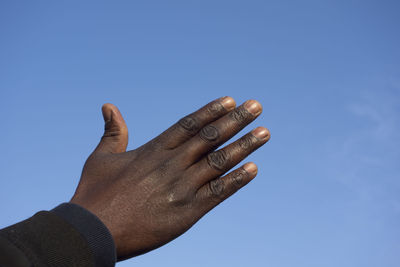 Close-up of hand against blue sky