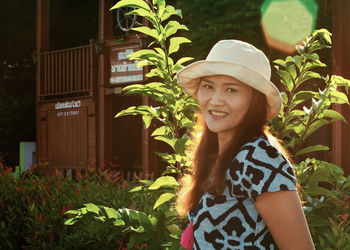 Portrait of smiling young woman standing against plants