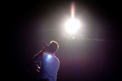 Rear view of musician singing against illuminated lights at night