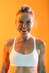 Portrait of young woman standing against yellow background
