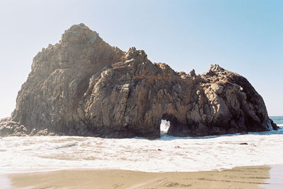 Rock formations on beach against clear sky