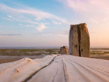 Surface level of wood at beach against sky