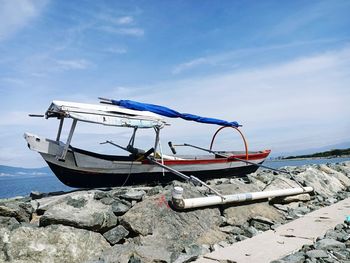 Fishing boat on beach against sky