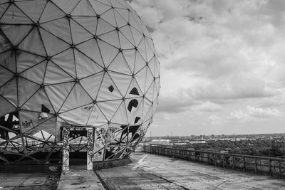 Metallic structure in city against cloudy sky