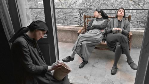 Women relaxing while sitting on bench at balcony