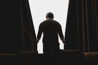 Rear view of man sitting on sofa at home