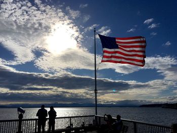 People flag by sea against sky