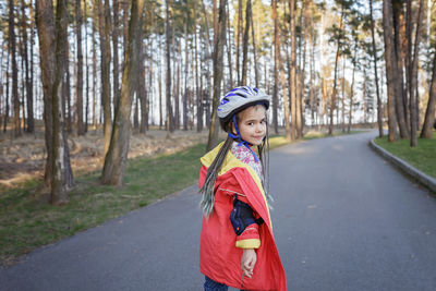 Portrait of girl standing on road amidst trees