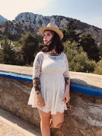 Portrait of beautiful young woman standing against trees