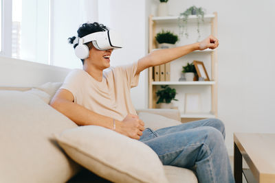 Young woman using mobile phone while sitting on sofa at home