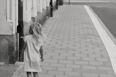 Rear view of girl standing on sidewalk