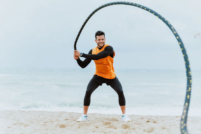 Male athlete exercising with rope at beach