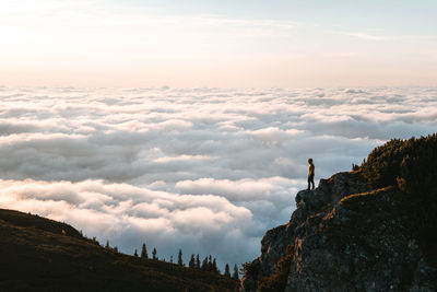 Man standing on rock against sky during sunset