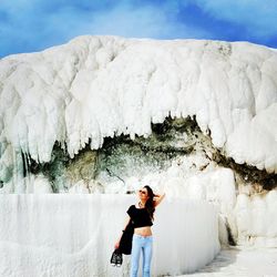 Fashionable young woman holding shoes against limestone at pamukkale