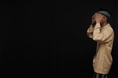Side view of a boy looking away over black background