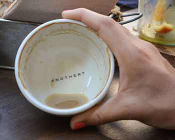 High angle view of hand holding tea cup on table