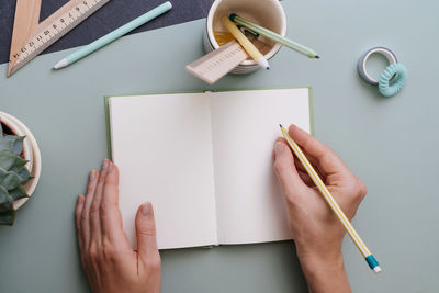 Cropped hands of woman writing in book