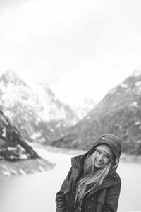 Portrait of smiling young woman against sky during winter