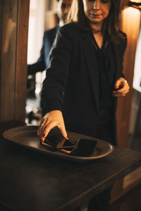 Midsection of female legal professional keeping smart phone on tray in office