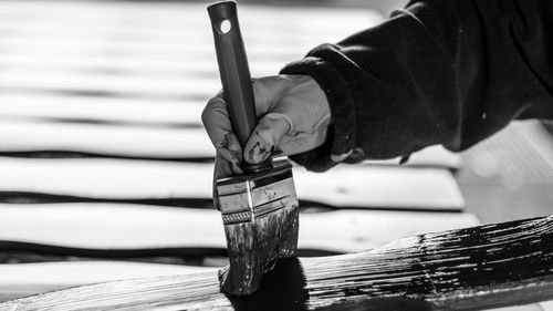 Cropped hands of person painting wood