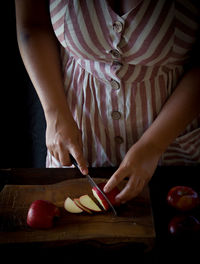 Midsection of woman eating food on cutting board