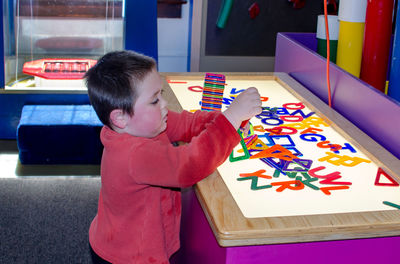 Young boy plays with acrylic colored letters on a light table