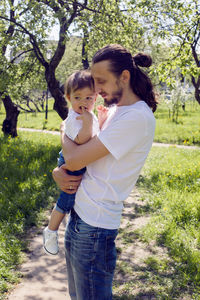 Father holds son in his arms in a blooming garden