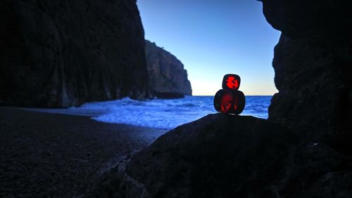 Man on cliff by sea against clear sky