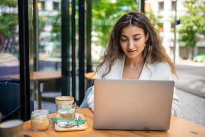 Young woman using laptop at cafe