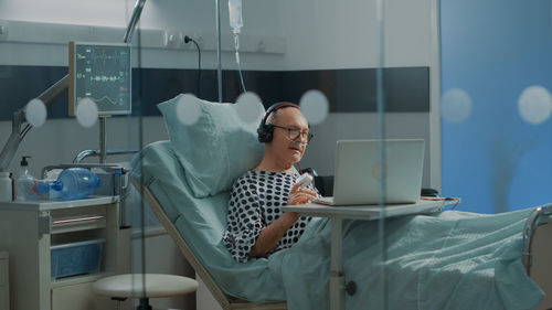 Portrait of young woman using mobile phone while standing in hospital