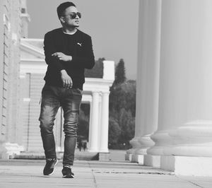 Full length portrait of young man standing against built structure