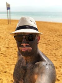 Portrait of man with mud on face and body standing at beach