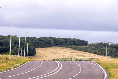 Road by trees against sky