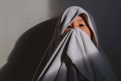 Portrait of boy wrapped in towel against wall
