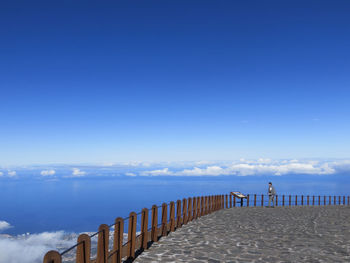 Man standing on observation point looking at sea against clear blue sky in tenerife